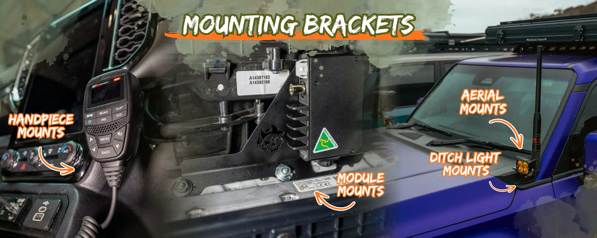 A close-up labeled photo of a vehicle-mounted hardware kit inside a blue vehicle cabin. Orange text callouts identify handpiece mounts, aerial mounts, ditch light mounts, and module mounts, with the title 'MOUNTING BRACKETS' across the top.
